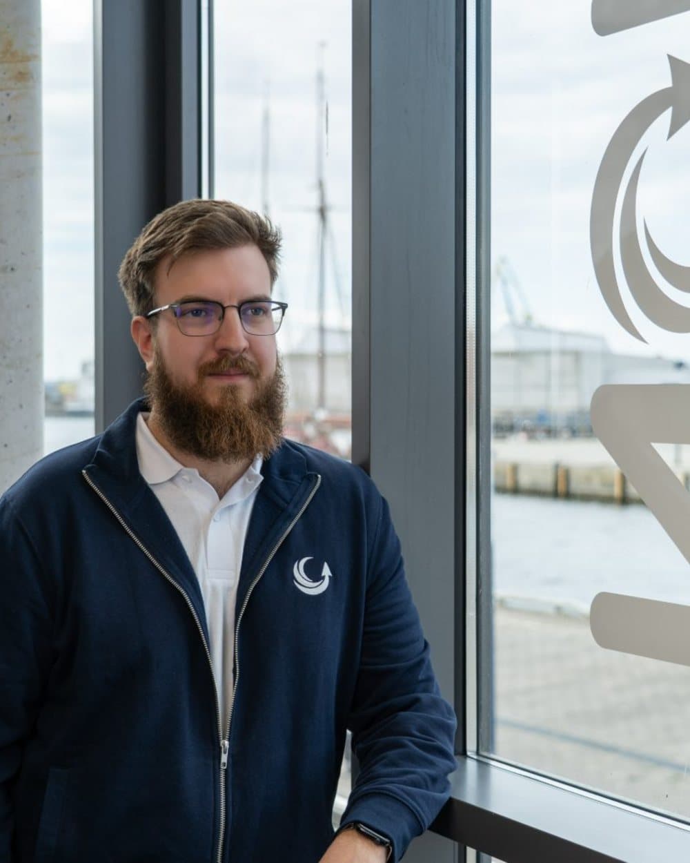 Simon Glowik am Fenster mit geätztem NordFlux-Logo